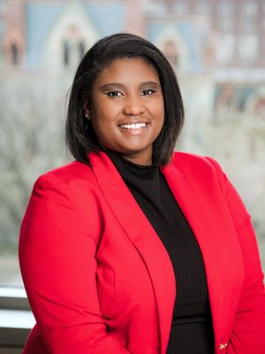 woman in red jacket standing in front of a university background